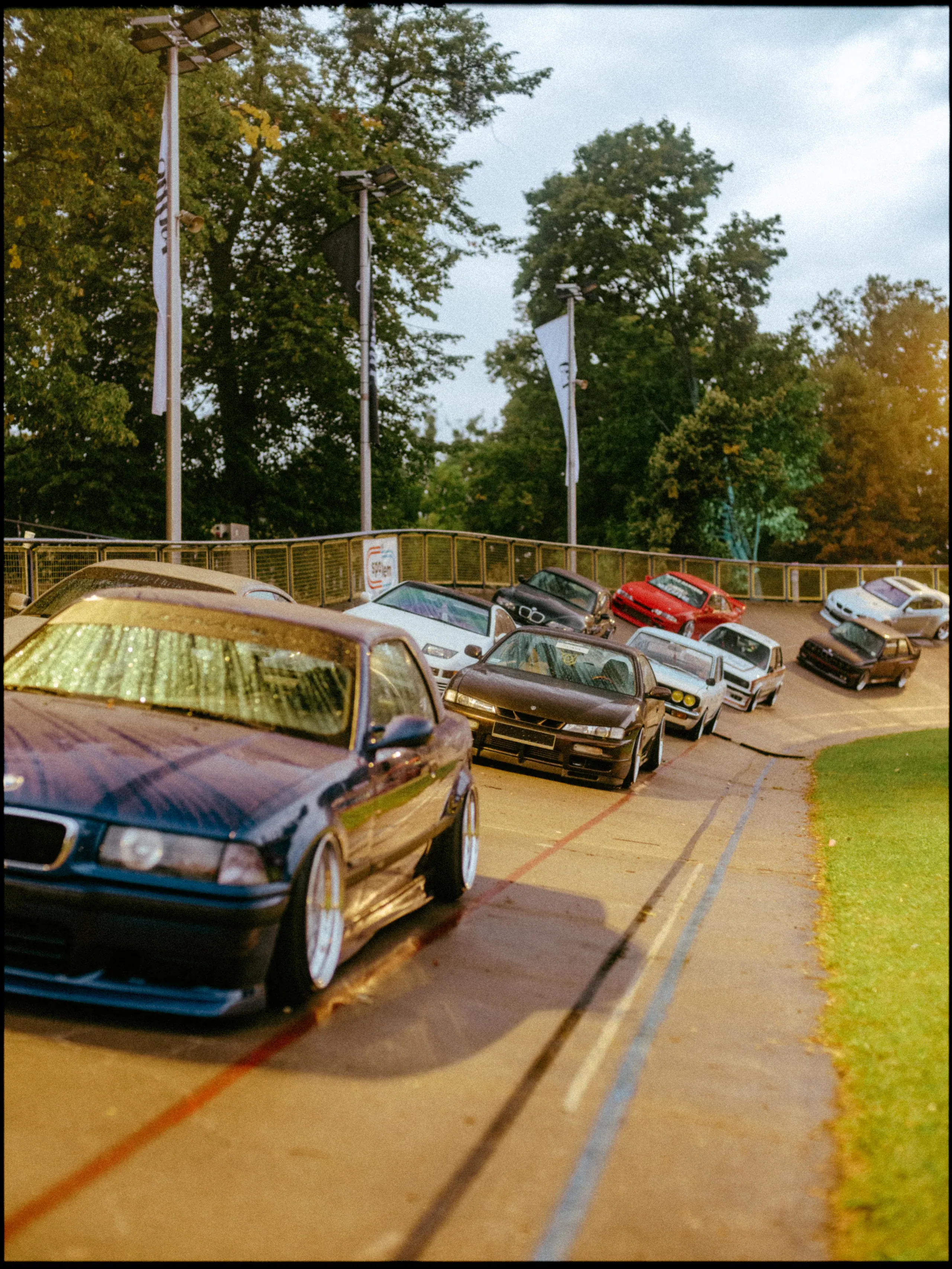 Colourful classic cars queued on a road around the event grounds.