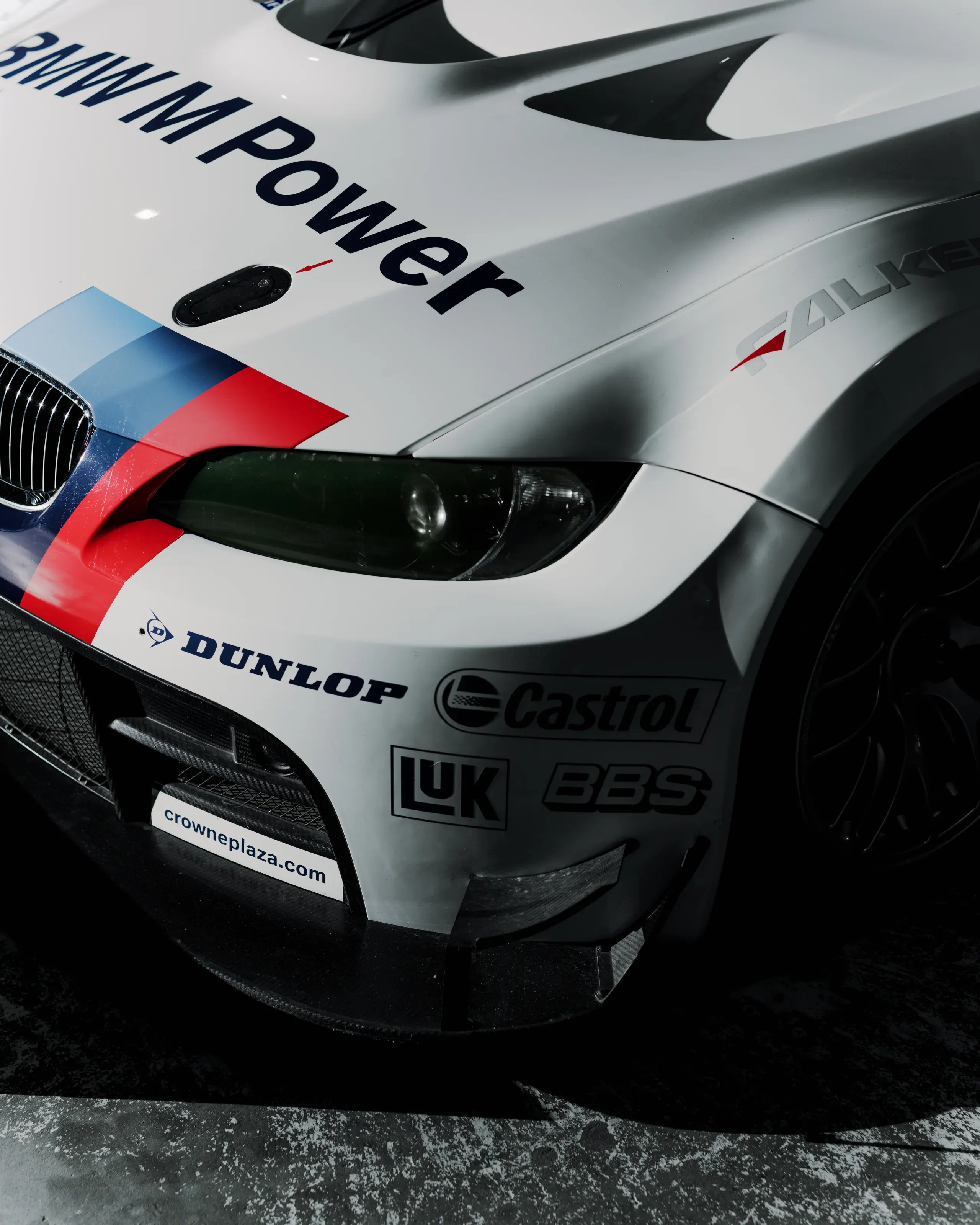 Wyścigowe BMW w białym malowaniu widziane z góry w ciemnej hali.