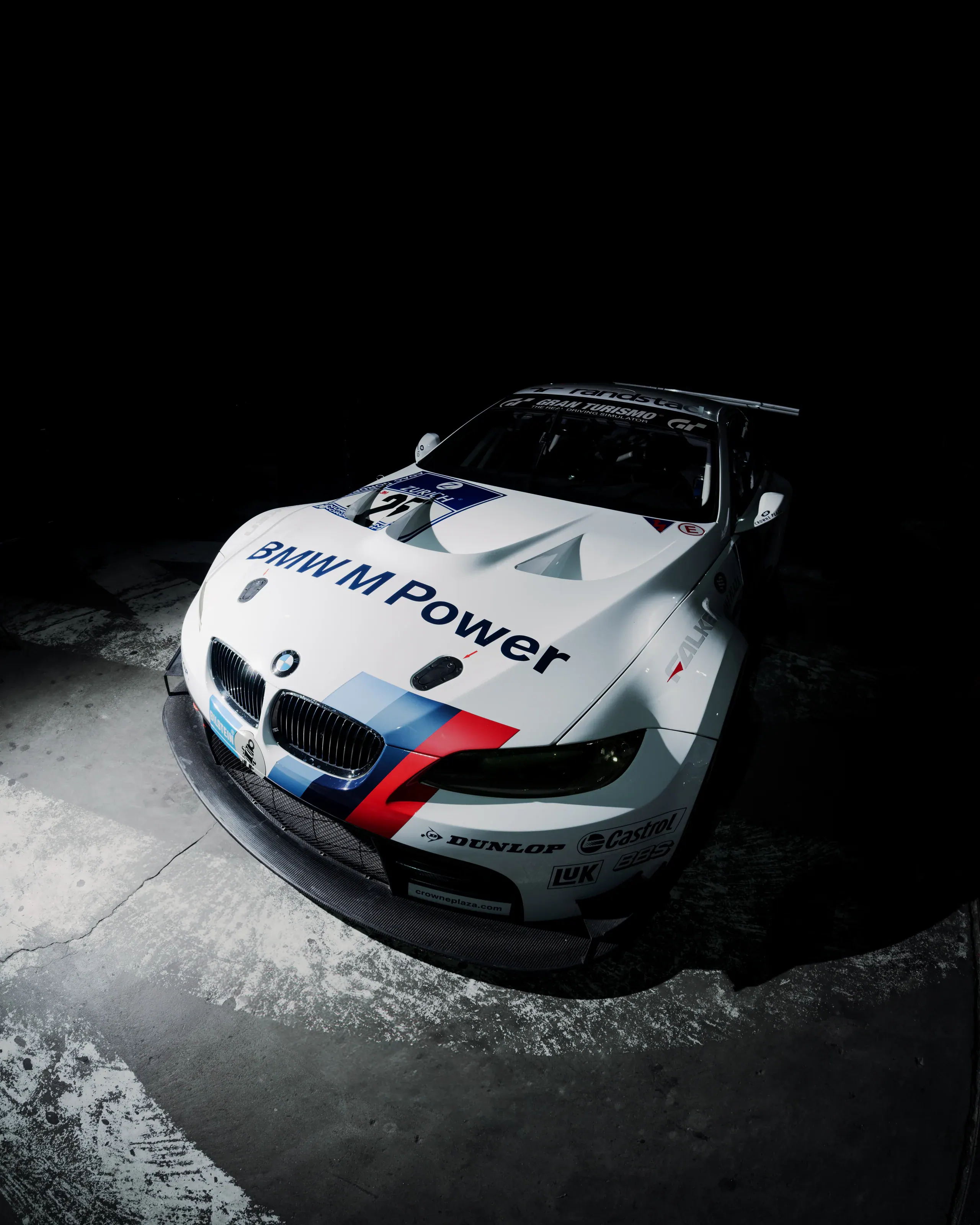 Białe wyścigowe BMW sfotografowane z przodu w ostrym świetle sceny.